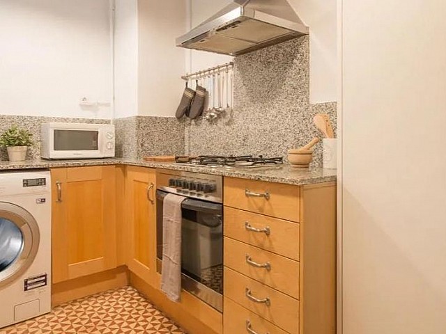 Cocina office con muebles de madera clara, lavadora y horno