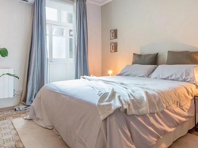 Dormitorio de matrimonio con cabecero tapizado y mesitas de noche