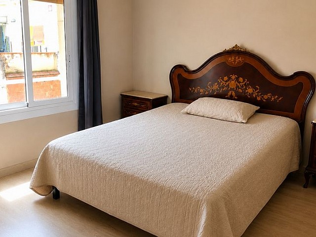 Dormitorio con cama doble, cabecero de madera oscura y ventana