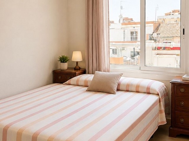Dormitorio con cama individual, mesita de noche y vistas a la calle