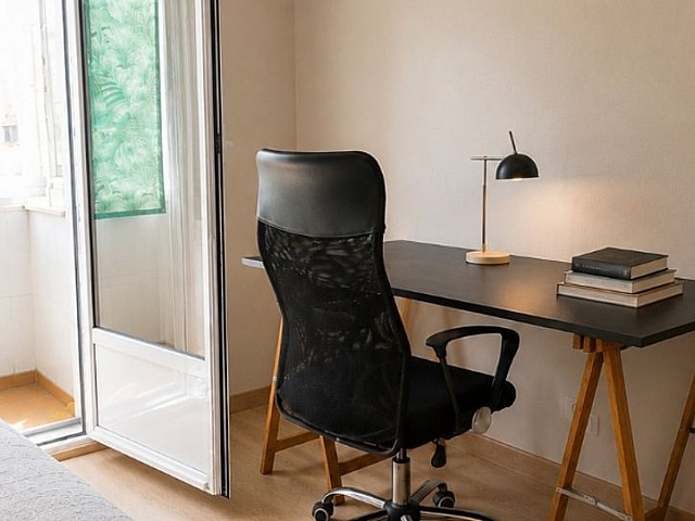 Habitación con escritorio, silla y ventana con luz natural