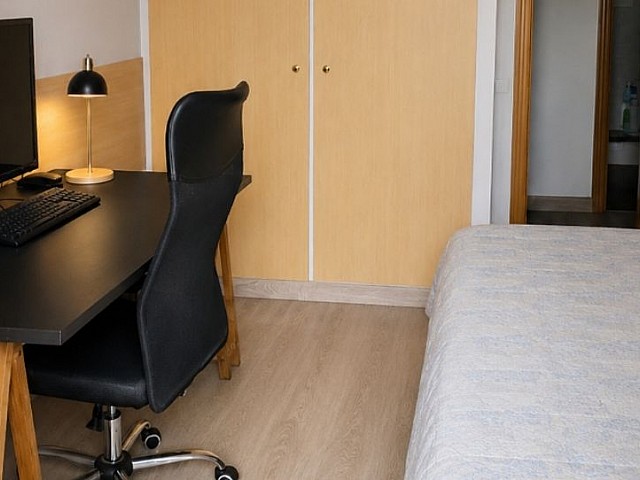 Habitación con mesa de escritorio, silla de oficina y cama individual