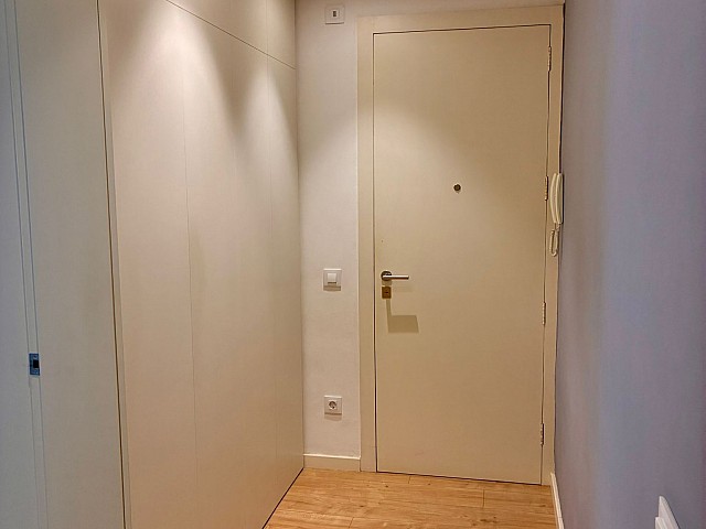 Recibidor o pasillo de entrada con iluminación mediante focos encastrados y puerta principal.