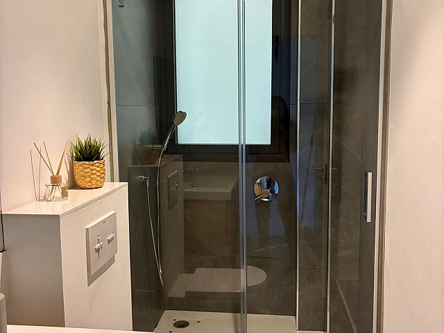 Vista del mueble de baño con lavabo, grifería moderna y contraste de azulejos claros y oscuros.