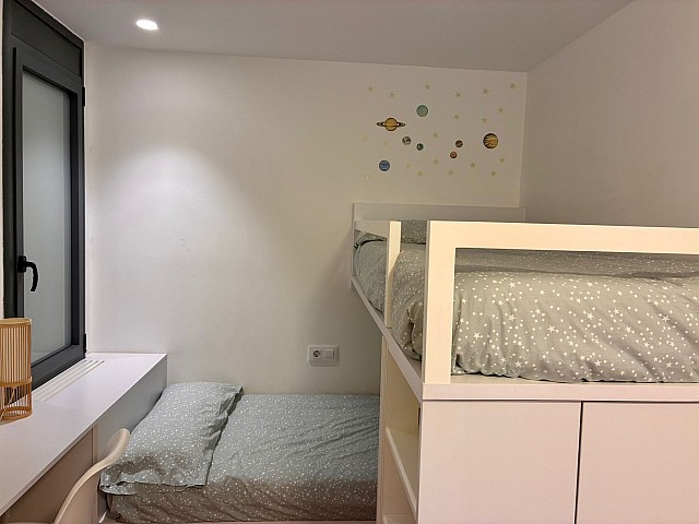 Ángulo de la habitación juvenil mostrando la cama y detalles decorativos en la pared.