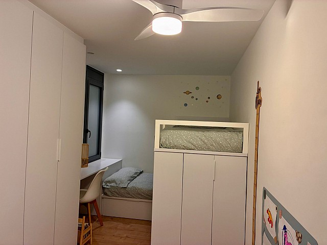 Habitación juvenil o infantil equipada con litera o cama elevada, armario a medida y ventilador de techo.