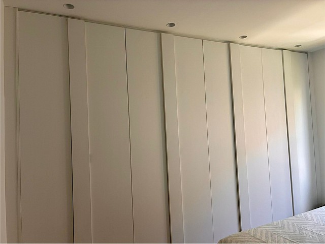 Detalle de las puertas correderas de un armario empotrado blanco de gran capacidad.