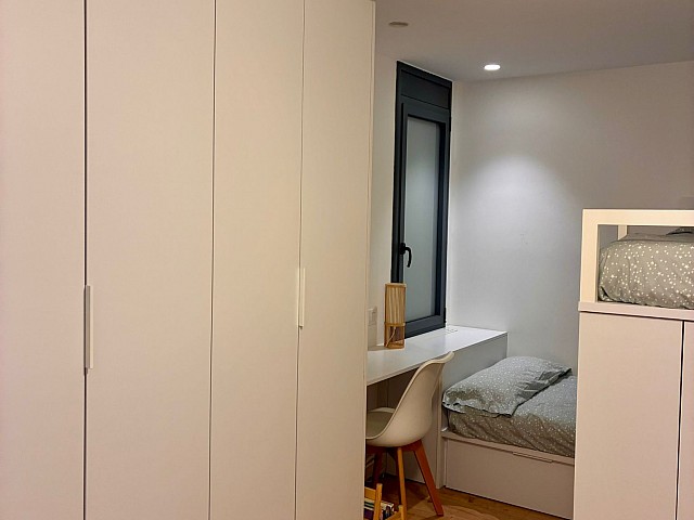 Vista de armario a medida y ventilador de techo en dormitorio.