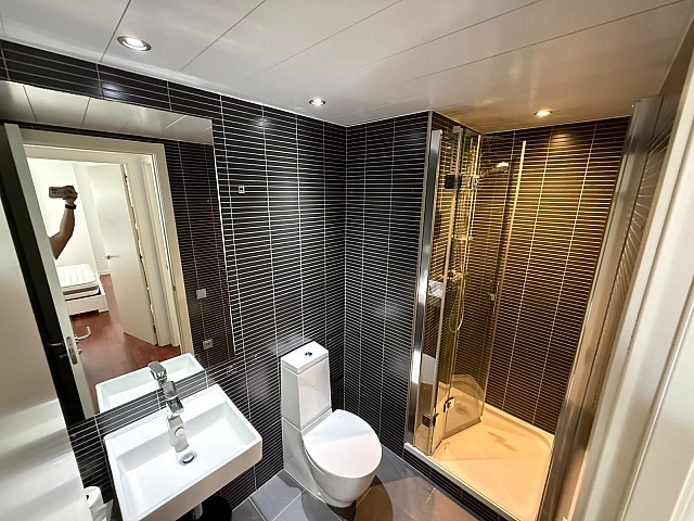 Baño completo con moderno revestimiento y zona de ducha.