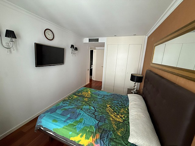 Dormitorio principal con armarios empotrados y televisión.