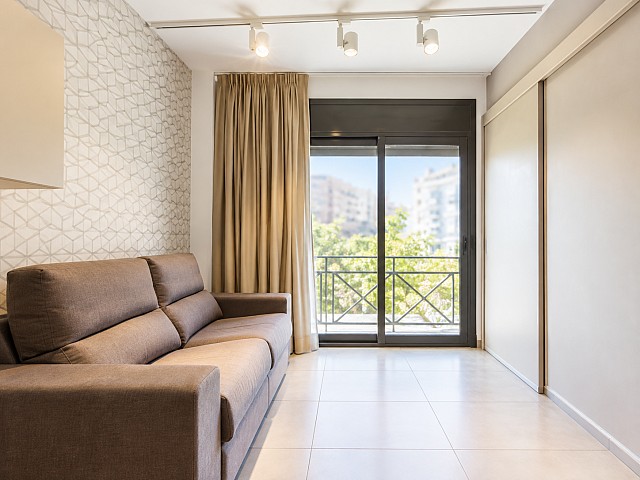 Salón con sofá y puerta acristalada de acceso al balcón