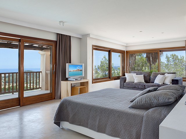 Уютная спальня с большими окнами и потрясающими видами на шикарной вилле в краткосрочную аренду на Ибице