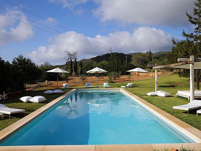 Majestuosa piscina en el jardín rodeada de hamacas 